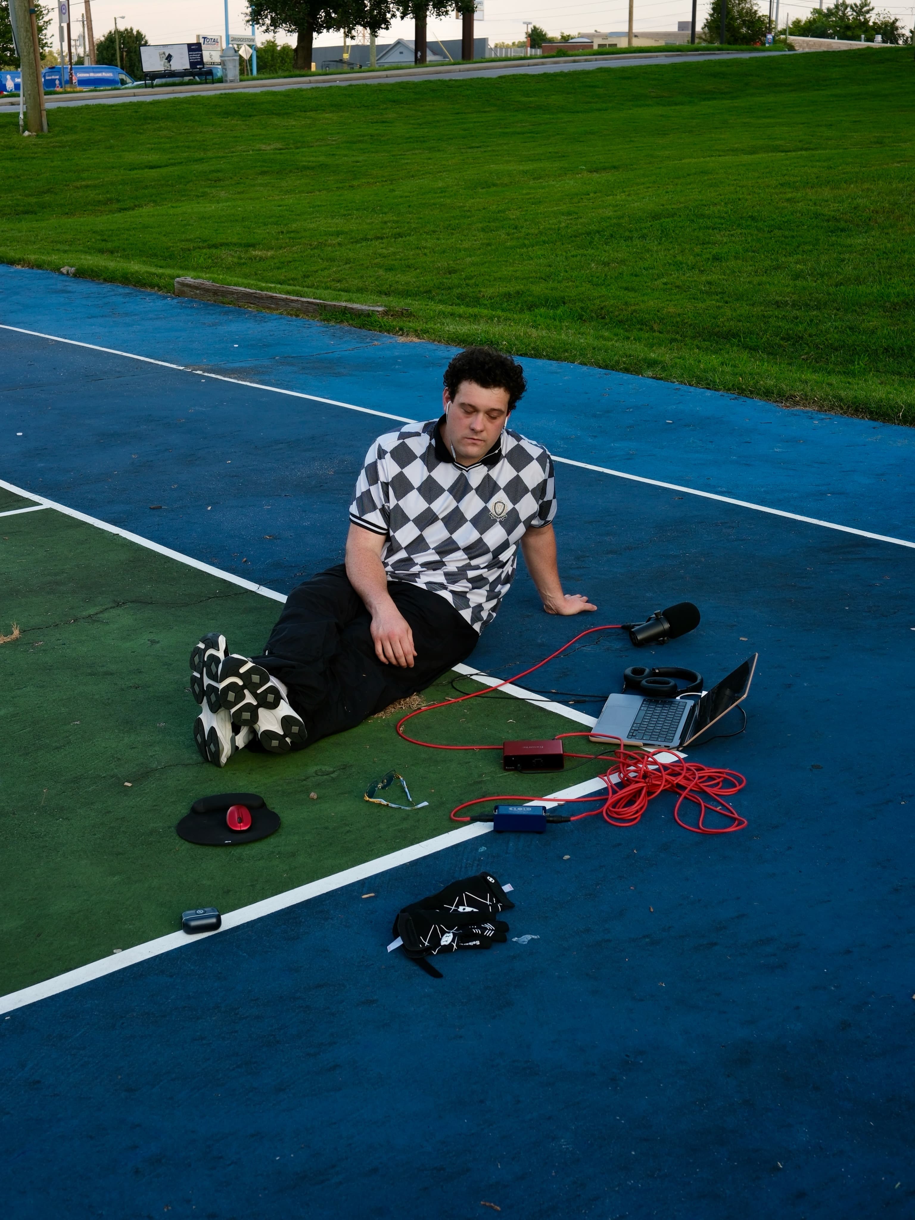 BRAVEN resting with his eyes closed beside a laptop and microphone on the blue court.